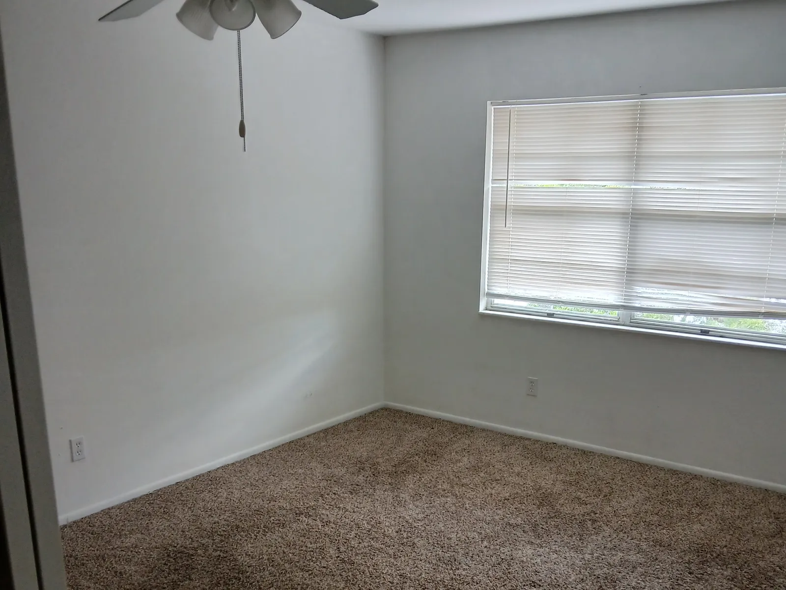 Empty bedroom with ceiling fan and window before the repaint