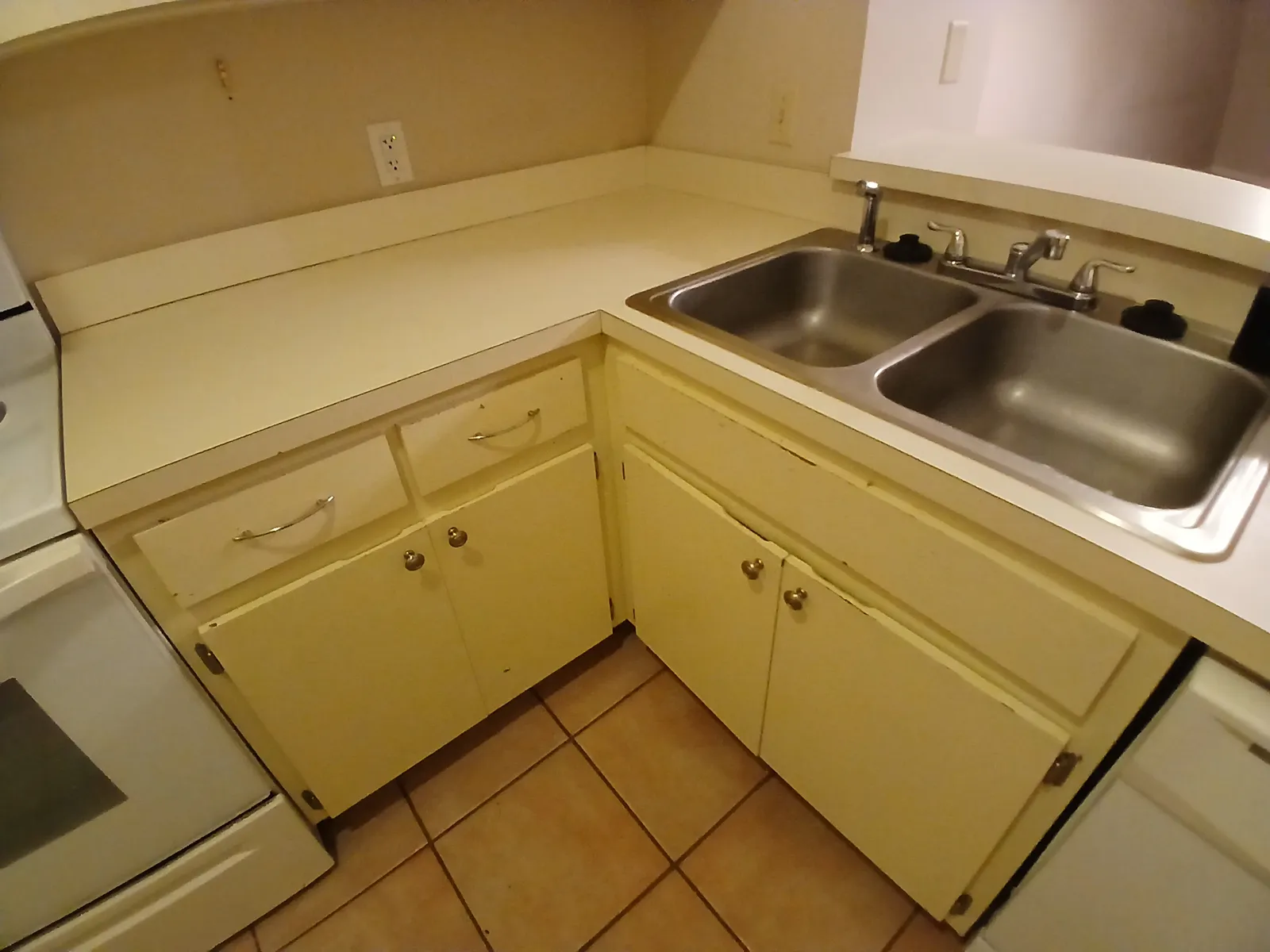 Kitchen corner with yellowed, worn cabinet paint before the repaint